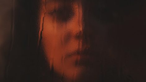 Woman's face seen through rain-streaked glass