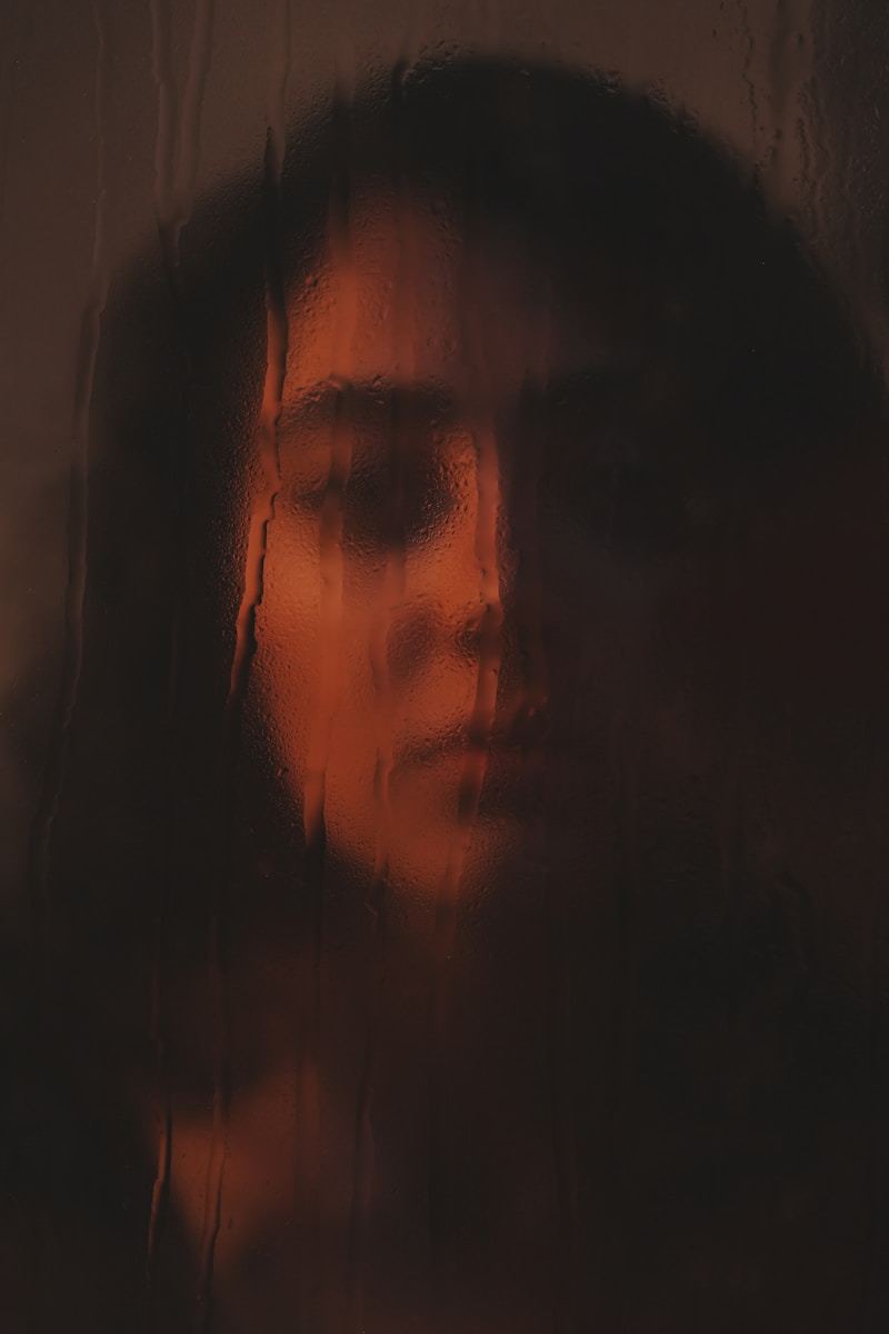 Woman's face seen through rain-streaked glass